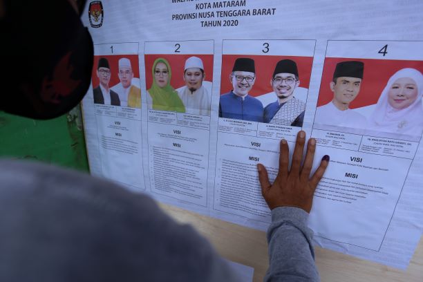 SUDAH NYOBLOS: Seorang pemilih membaca visi misi calon Wali Kota dan Wakil Wali Kota Mataram setelah mencoblos di TPS 4 Gomong Lama, Kota Mataram, Rabu (9/12/20) lalu. (IVAN/LOMBOK POST)