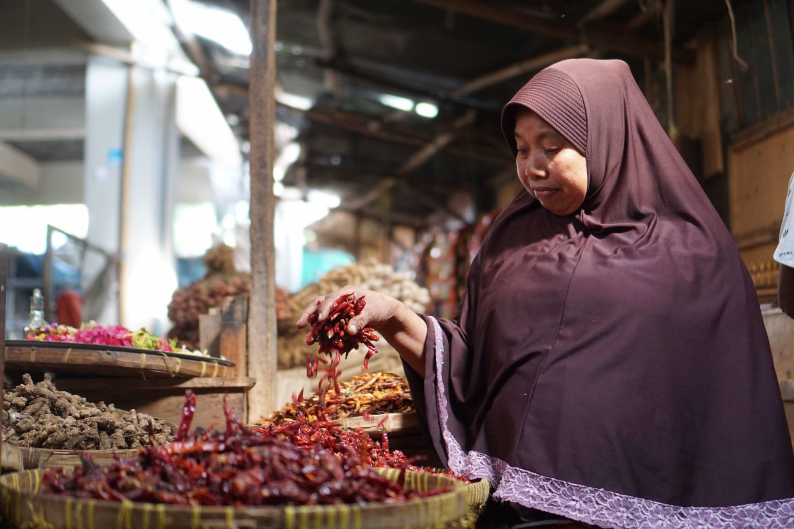 NAIK LAGI: Pedagang sedang membungkus cabai jualannya untuk pembeli di Pasar Aikmel, belum lama ini. (Foto: Fatih/Lombok Post)