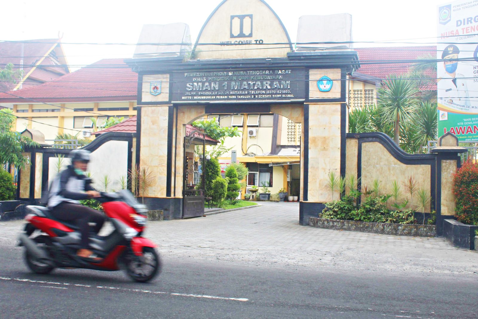 HENTIKAN AKTIVITAS: Seorang pengendara melintas di depan SMAN 1 Mataram, kemarin (8/1). Sekolah ini mengehentikan layanan pembelajaran sementara, karena siswanya dikonfirmasi positif Covid-19.
