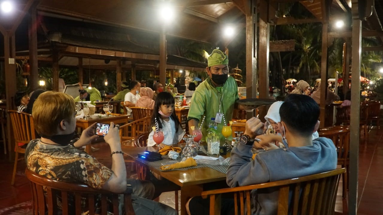 MULAI MENGGELIAT: Seorang pelayan sedang menghidangkan sajian makanan ke salah satu meja tamu di salah satu hotel di Senggigi, beberapa hari lalu. (rami for lombok post)