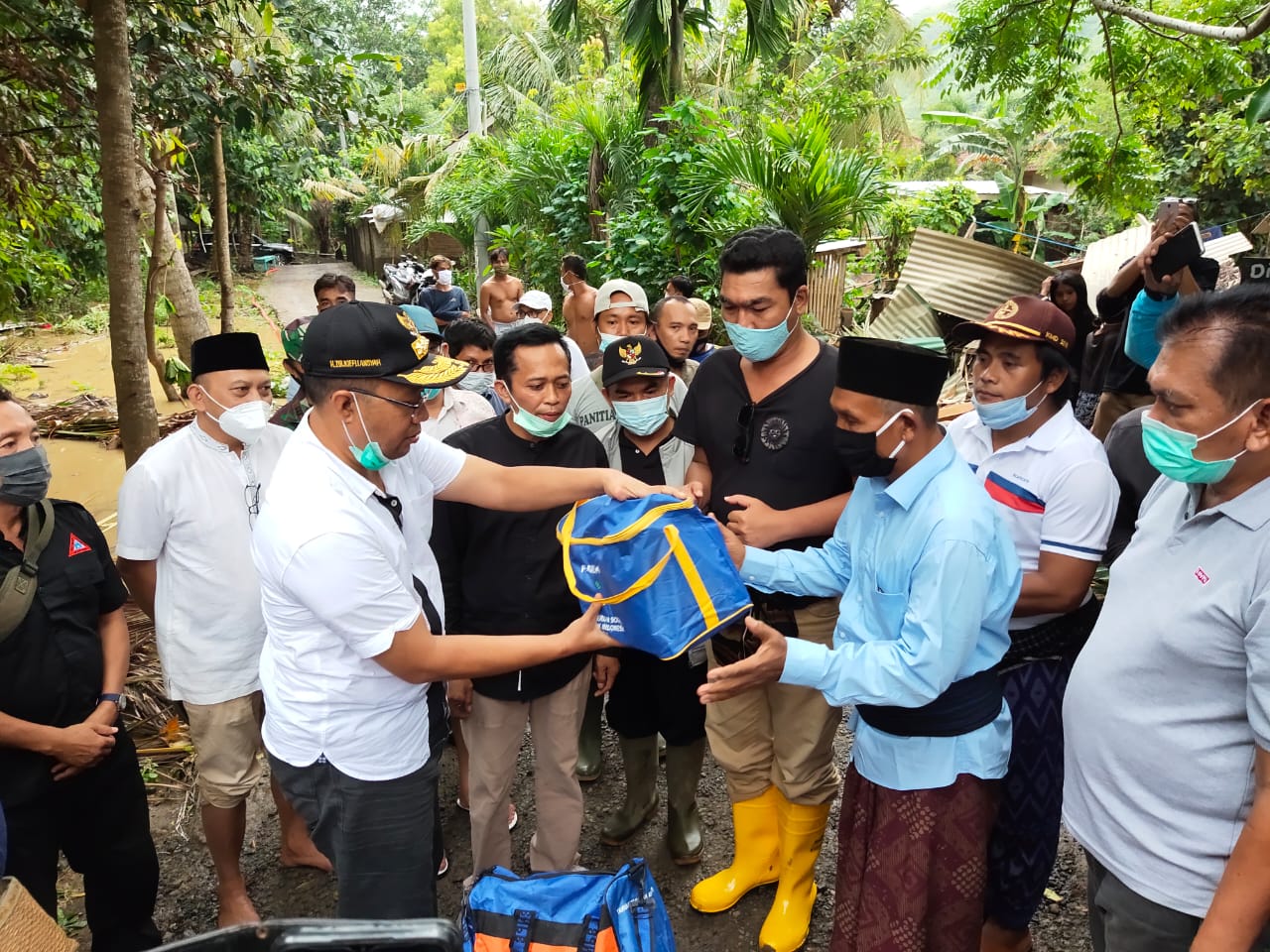 BANTU KORBAN BANJIR: Gubernur NTB H Zulkieflimansyah (kiri baju putih) menyerahkan bantuan secara simbolis kepada korban banjir di Desa Kuta, Lombok Tengah, Minggu (31/1). (Diskominfotik NTB for Lombok Post)