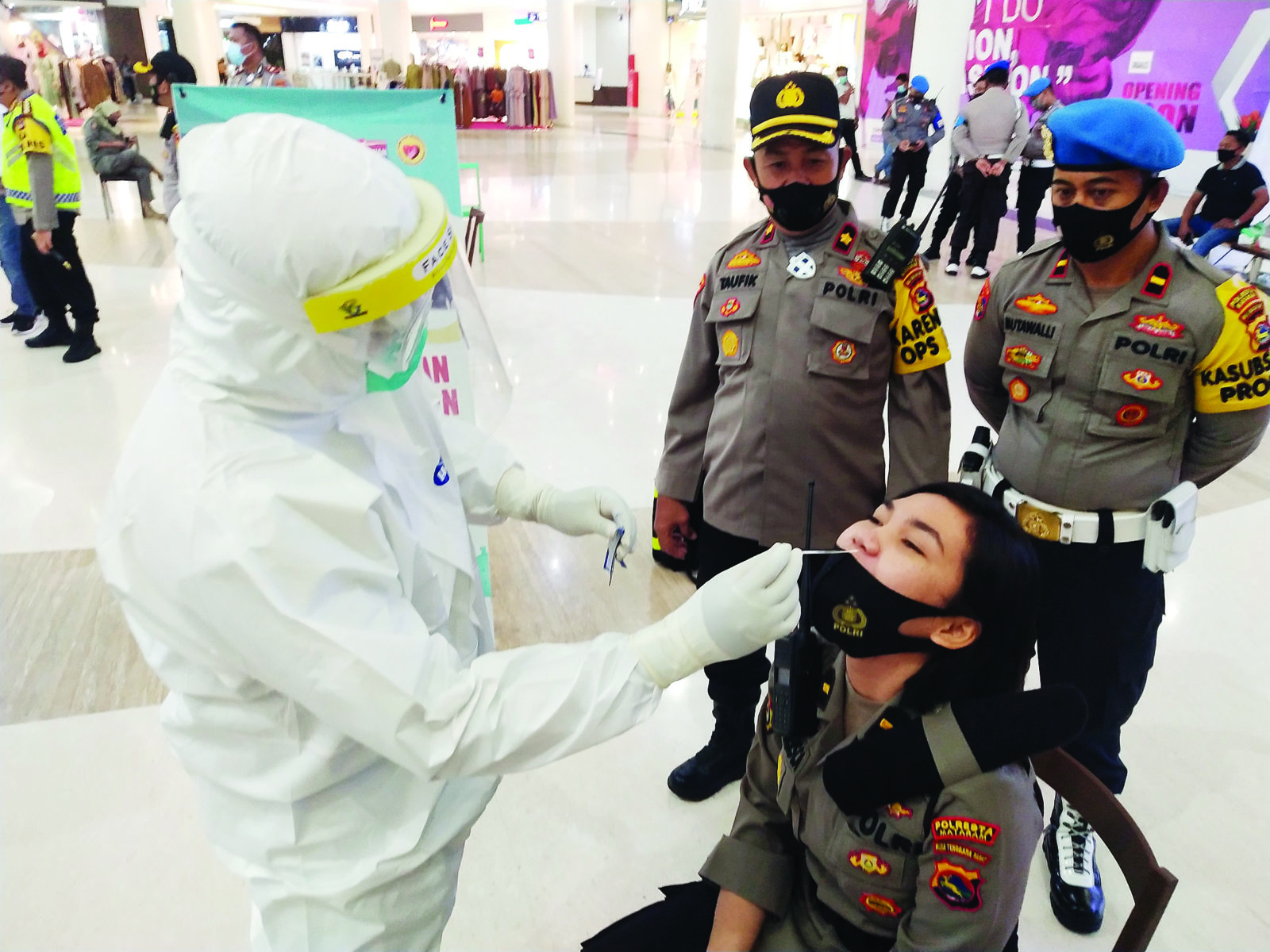HARLI/LOMBOK POST LAWAN COVID-19: Petugas mengambil sampel lendir dari hidung seorang polwan Polresta Mataram yang menjalani rapid test antigen di Lombok Epicentrum Mall, Sabtu malam (16/1). (harli/lombok post)