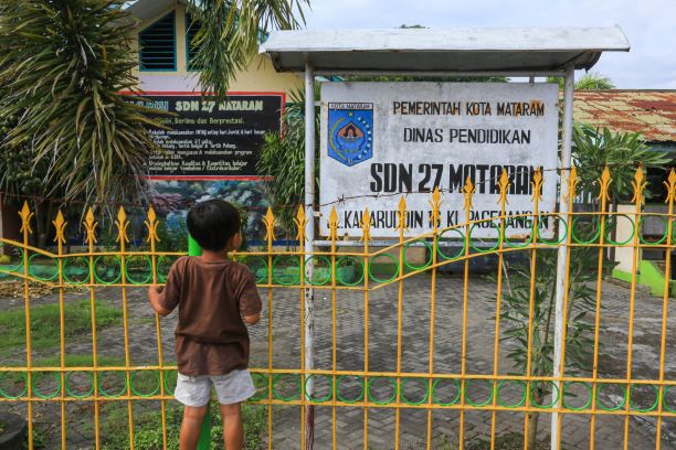 RINDU BERSEKOLAH: Seorang anak mengintip sekolahnya di SDN 27 Mataram, Pagesangan, Kota Mataram. Terlalu lama libur membuat anak anak rindu suasana sekolah. (IVAN/LOMBOK POST )