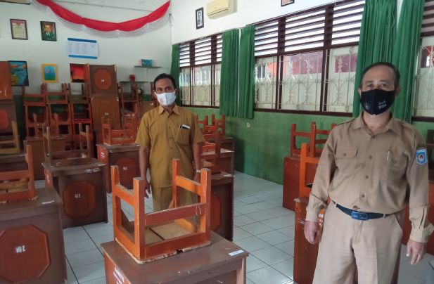 SIAP BELAJAR TATAP MUKA: Kepala SMPN 2 Mataram M Nazuhi (kanan) menunjukkan penataan meja sesuai protokoler Covid-19, Senin (4/12) lalu.( TONI/LOMBOK POST)