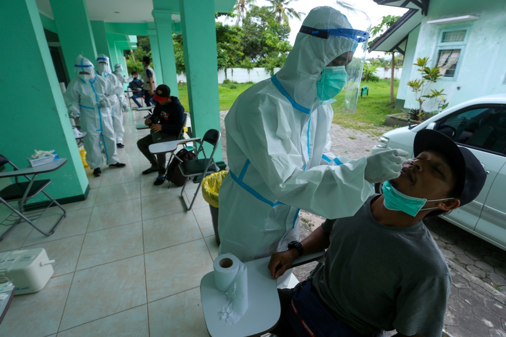 SWAB PERTAMA: Petugas kesehatan melakukan tes swab kepada PMI yang baru sampai di rumah sakit darurat di Asrama Haji NTB, Kota Mataram, Kamis (7/1). (Foto: Ivan/Lombok Post)