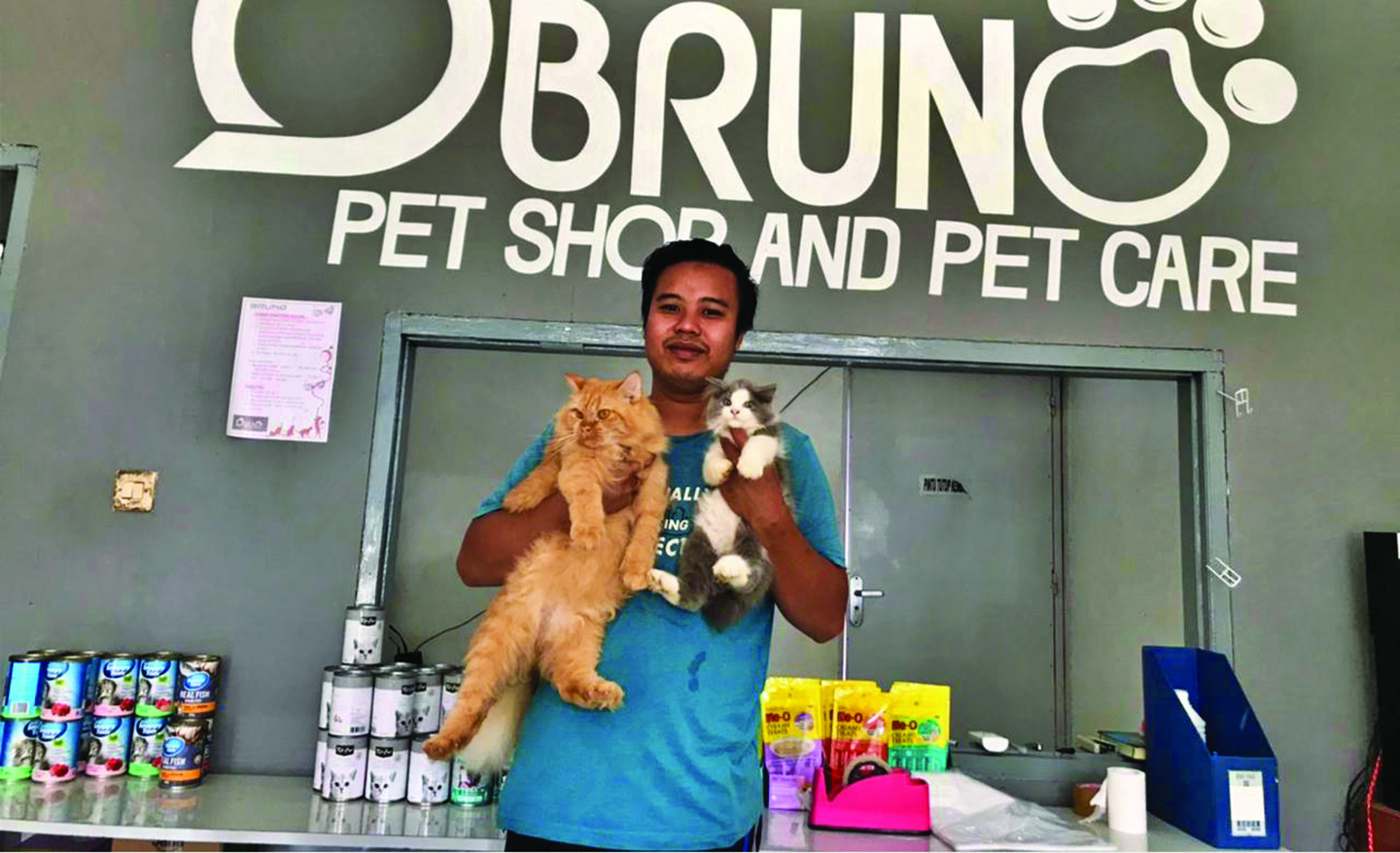PET SHOP: Muhammad Saufi Hidayat, groomer Bruno Pet Shop and Pet Care berfoto bersama kucing customer yang dirawatnya di Kelurahan Selong, Kecamatan Selong, Selasa (16/3/2021). (Fatih/Lombok Post)