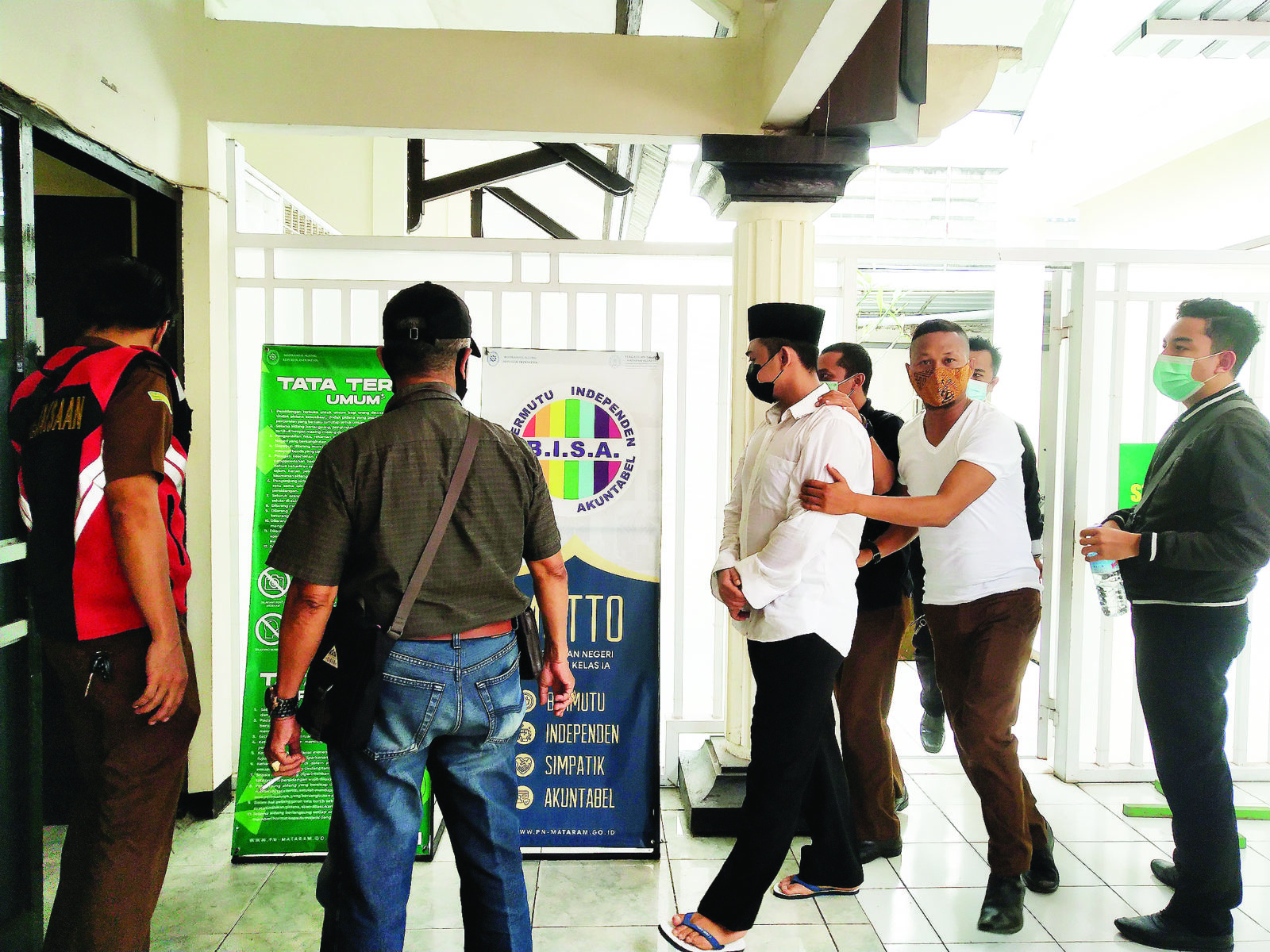 DIKAWAL KETAT: Terdakwa kasus pembunuhan Rio Prasetya (berpeci) digiring menuju ruang persidangan di Pengadilan Negeri Mataram, Kamis (25/2/2021) lalu. (Harli/Lombok Post)