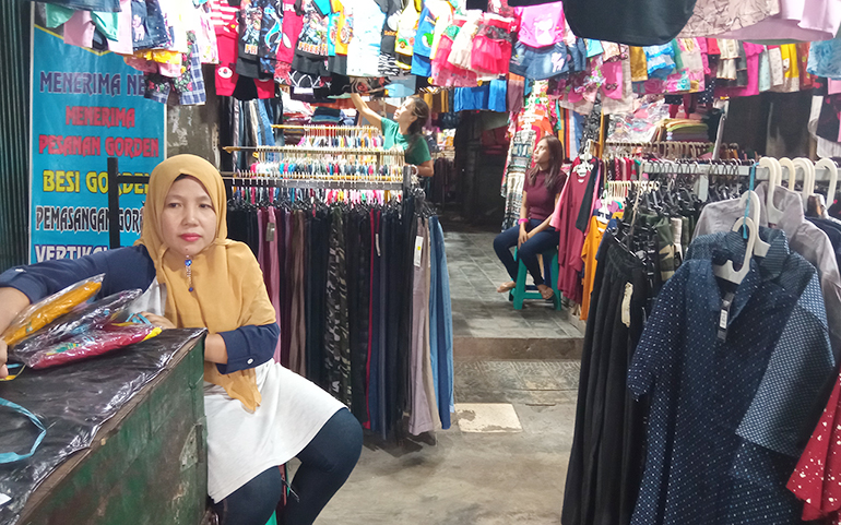 MENUNGGU PEMBELI: Sulpiah, salah satu pedagang Pasar Cakranegara menunggu pembeli datang. Warga yang biasanya beramai-ramai datang membeli baju persiapan Lebaran di bulan Ramadan ke Pasar Cakranegara, kini mulai menurun drastis. (Toni/Lombok Post)