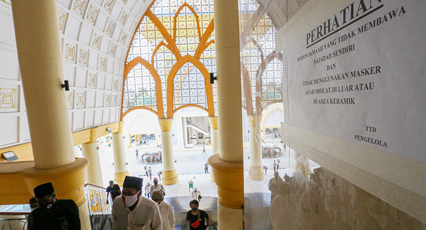 TERAPKAN PROKES: Pengurus Masjid Hubbul Wathan Islamic Centre menempelkan aturan bagi warga yang tidak membawa sajadah atau tidak memakai masker agar melaksanakan salat di luar.