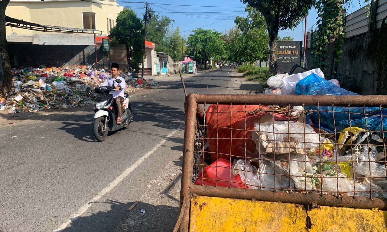 BAUNYA MENYENGAT: Seorang pengendara melintas diantara tumpukan sampah di jalan Batu Bolong, Pagutan, Kota Mataram, Selasa (18/5/2021).