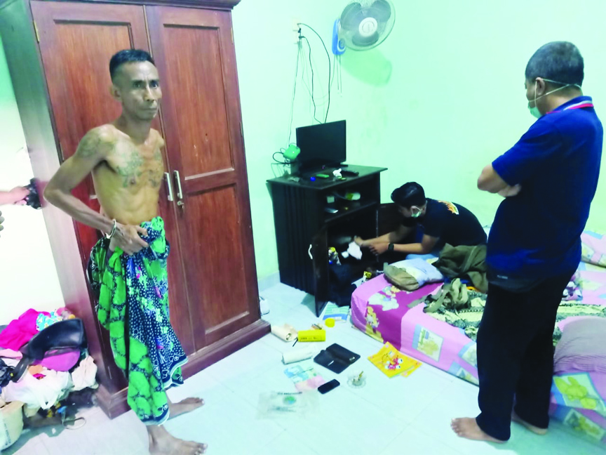 CARI SABU: Terduga pengedar sabu Sumana (kiri) menyaksikan proses penggeledahan yang dilakukan polisi di rumahnya di Abian Tubuh, Kelurahan Cakranegara Selatan, Mataram, Jumat dini hari (7/5/2021). (Harli/Lombok Post)