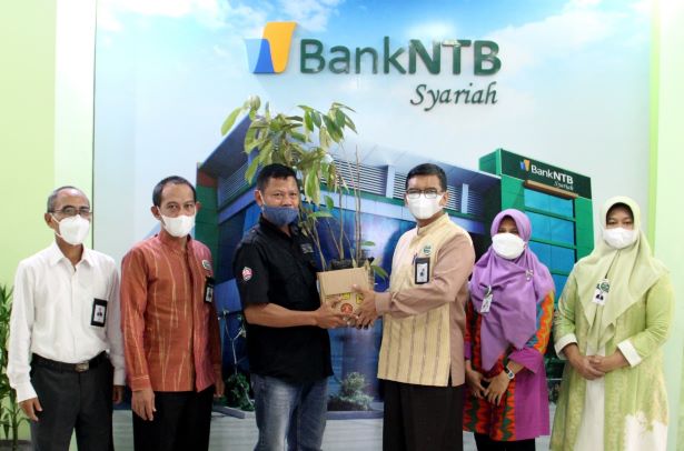 MENYELAMATKAN BUMI GORA: Direktur Utama Bank NTB Syariah H Kukuh Rahardjo (tiga dari kanan) menyerahkan secara simbolis bibit durian untuk penghijauan hutan kepada Ketua LPKB Dompu Burhan di Kantor Pusat Bank NTB Syariah, Selasa (25/5).( BANK NTB SYARIAH
