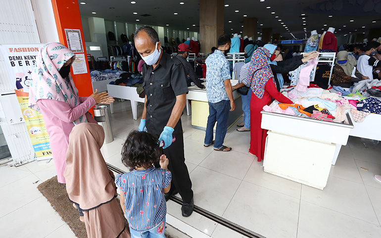 TERAPKAN PROKES: Petugas di salah satu pusat perbelanjaan di Kawasan Bisnis Cakranegara, Mataram, memeriksa suhu tubuh pengunjung sebelum masuk ke dalam toko. (Ivan/Lombok Post)