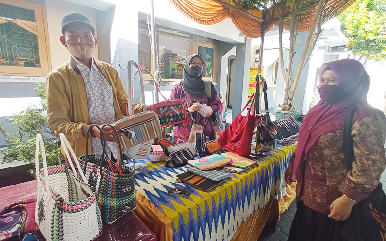 KREATIF: Wahidin (kiri), perajin tas dan dompet asal Dasan Agung, Mataram, saat memamerkan produknya dalam bazar yang digelar di halaman Kantor Dinas Koperasi dan UMKM Kota Mataram belum lama ini. (Toni/Lombok Post)