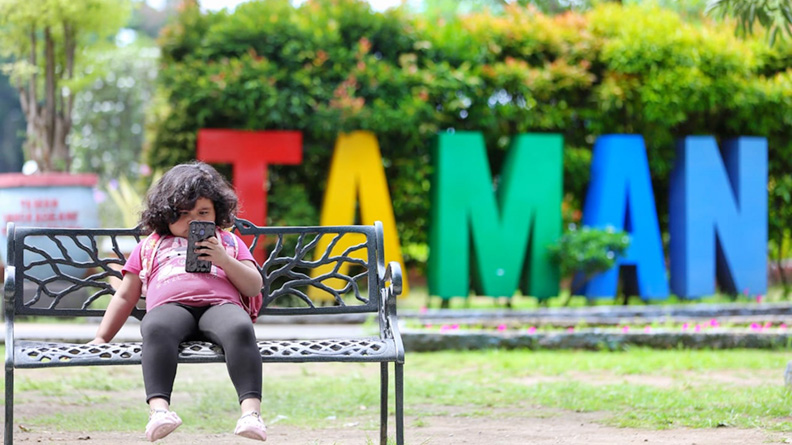 Seorang anak asyik bermain gawai di Taman Sangkareang, Kota Mataram. (Dok/Lombok Post)