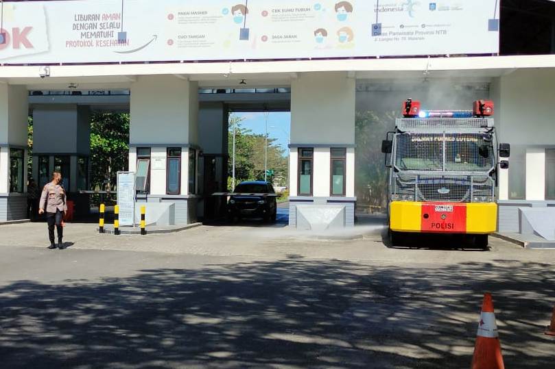 PENYEMPROTAN DISINFEKTAN: Mobil water cannon Polres Loteng saat melakukan penyemprotan disinfektan di bandara, Rabu (7/7). (Dedi/Lombok Post)