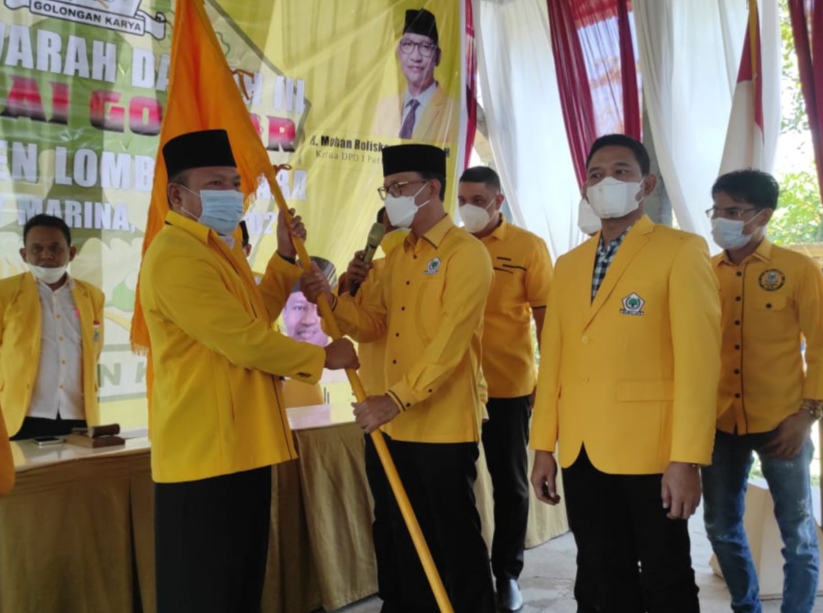 AKLAMASI: Ketua DPD I Golkar NTB H Mohan Roliskana (kanan) menyerahkan bendera Golkar pada Ketua DPD II Golkar Lombok Utara Mariadi yang terpilih secara aklamasi dalam Musda III DPD II Golkar Lombok Utara, di Hotel Medana Bay Marina, kemarin (14/7).( FERI