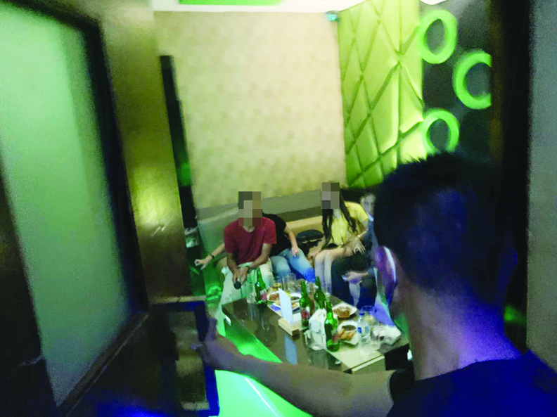 TIDAK TAAT: Kapolsek Cakranegara Kompol Nasrullah (membelakangi kamera) membuka pintu ruang karaoke dan mendapati sejumlah tamu sedang asyik karaoke bersama partner song di salah satu tempat hiburan malam di Mataram, Sabtu malam (17/7) lalu. (Harli/Lombok