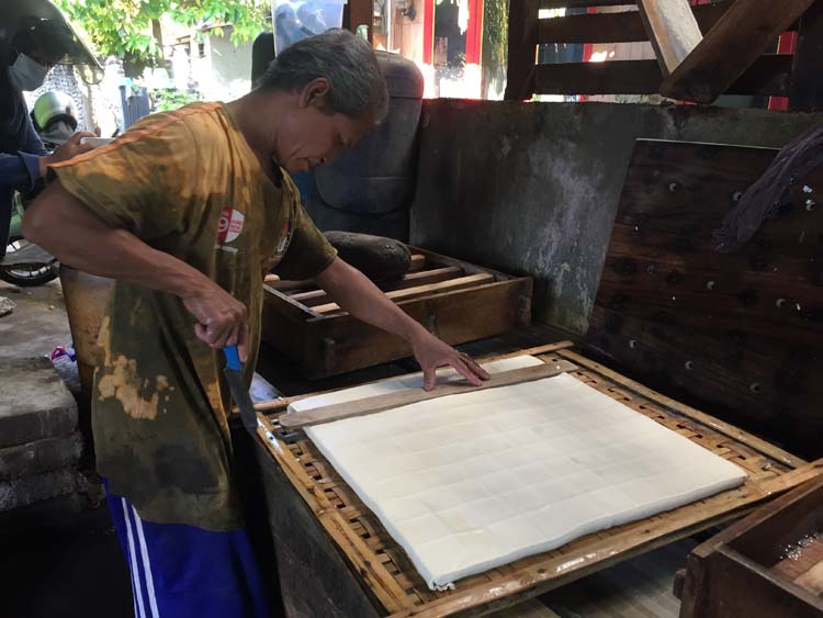 POTONG TAHU: Salah satu karyawan perajin tahu tempe di Kekalik, melakukan proses pembuatan tahu tempe
