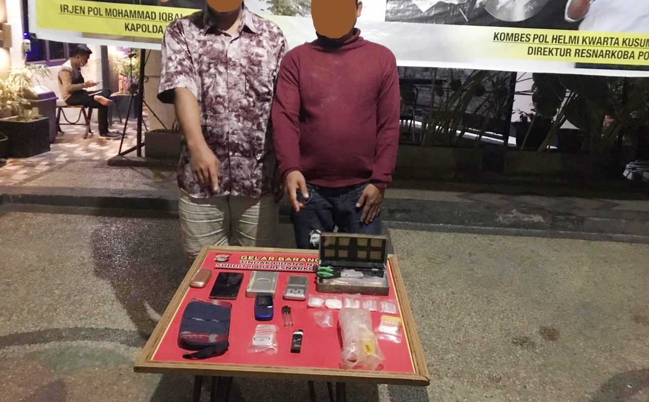 JANGAN DITIRU: Terduga pengedar sabu berinisial M (kanan) dan anaknya AW menunjukkan barang bukti sabu di Ditresnarkoba Polda NTB, Senin (23/8) dini hari.  (Harli/Lombok Post)