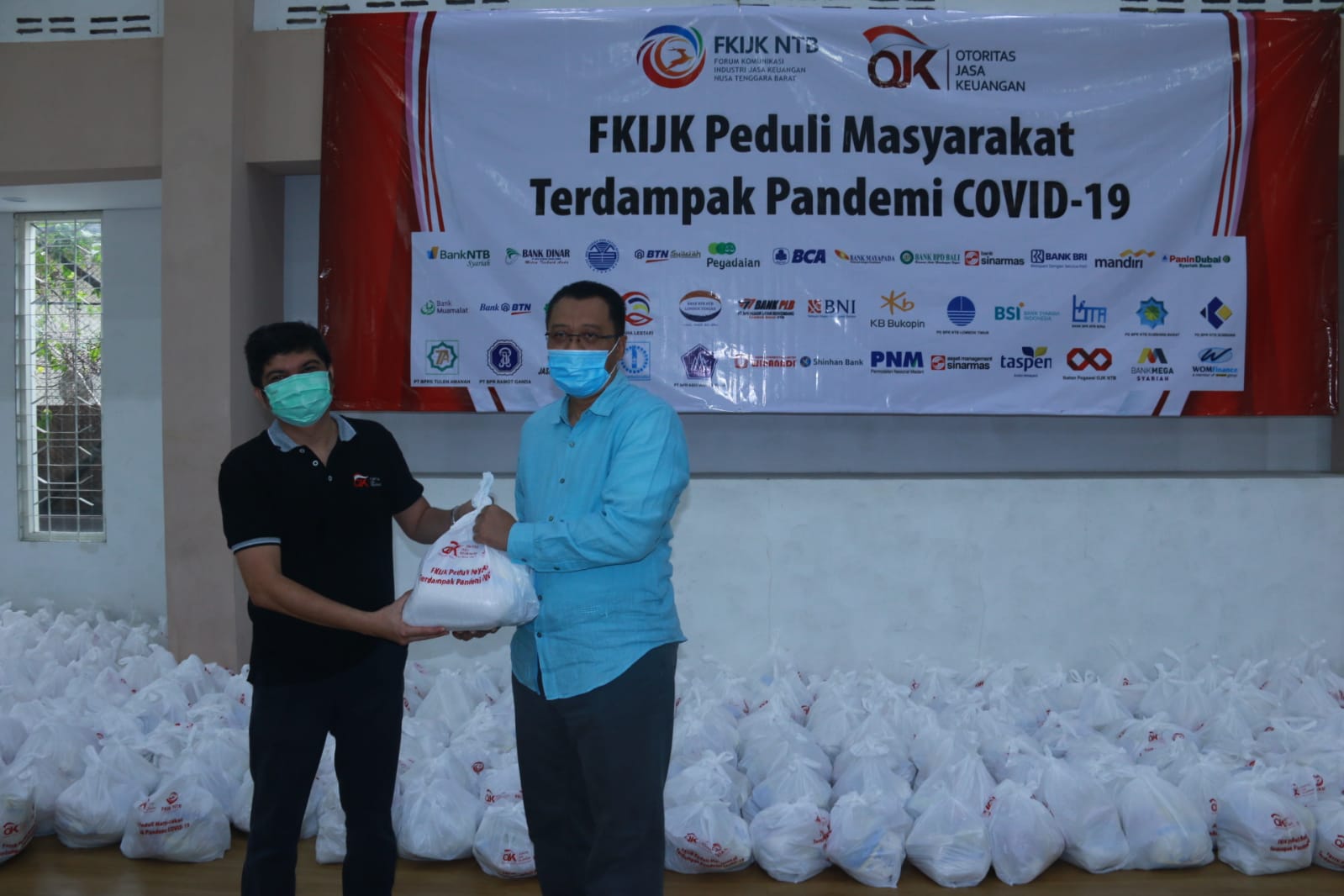 BANTU SESAMA: Kepala OJK NTB Rico Rinaldy (kiri) menyerahkan simbolis bantuan FKIJK NTB ke Gubernur NTB H Zulkieflimansyah untuk masyarakat NTB di GOR Griya Mandiri Jalan Langko di Mataram, Sabtu (11/9/2021).