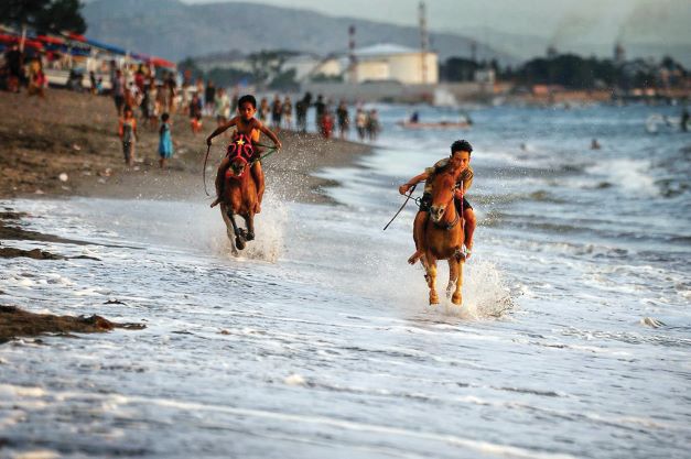 JADI DAYA TARIK: Dua joki cilik memacu kuda di Pantai Bintaro yang berbatasan dengan Pantai Meninting, Kota Mataram, Rabu (29/9) lalu. Pacuan kuda menjadi magnet wisatawan untuk berkunjung.( IVAN/LOMBOK POST)