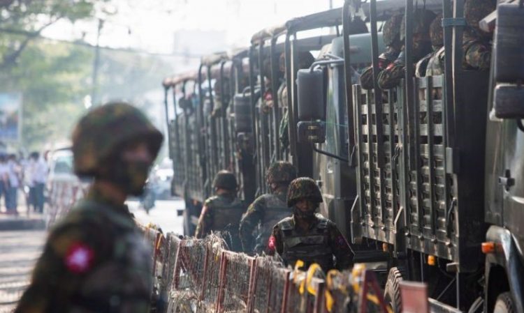 Tentara Myanmar berdiri di samping kendaraan militer ketika orang-orang berkumpul untuk memprotes kudeta militer di Yangon (REUTERS/Stringer)