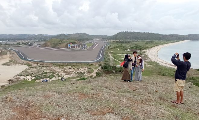 JADI PRIMADONA: Sejumlah wisatawan berfoto di Bukit Seger dengan latar Sirkuit Mandalika. Bukit Seger kini sedang jadi primadona baru wisatawan lokal.( TONI/LOMBOK POST)