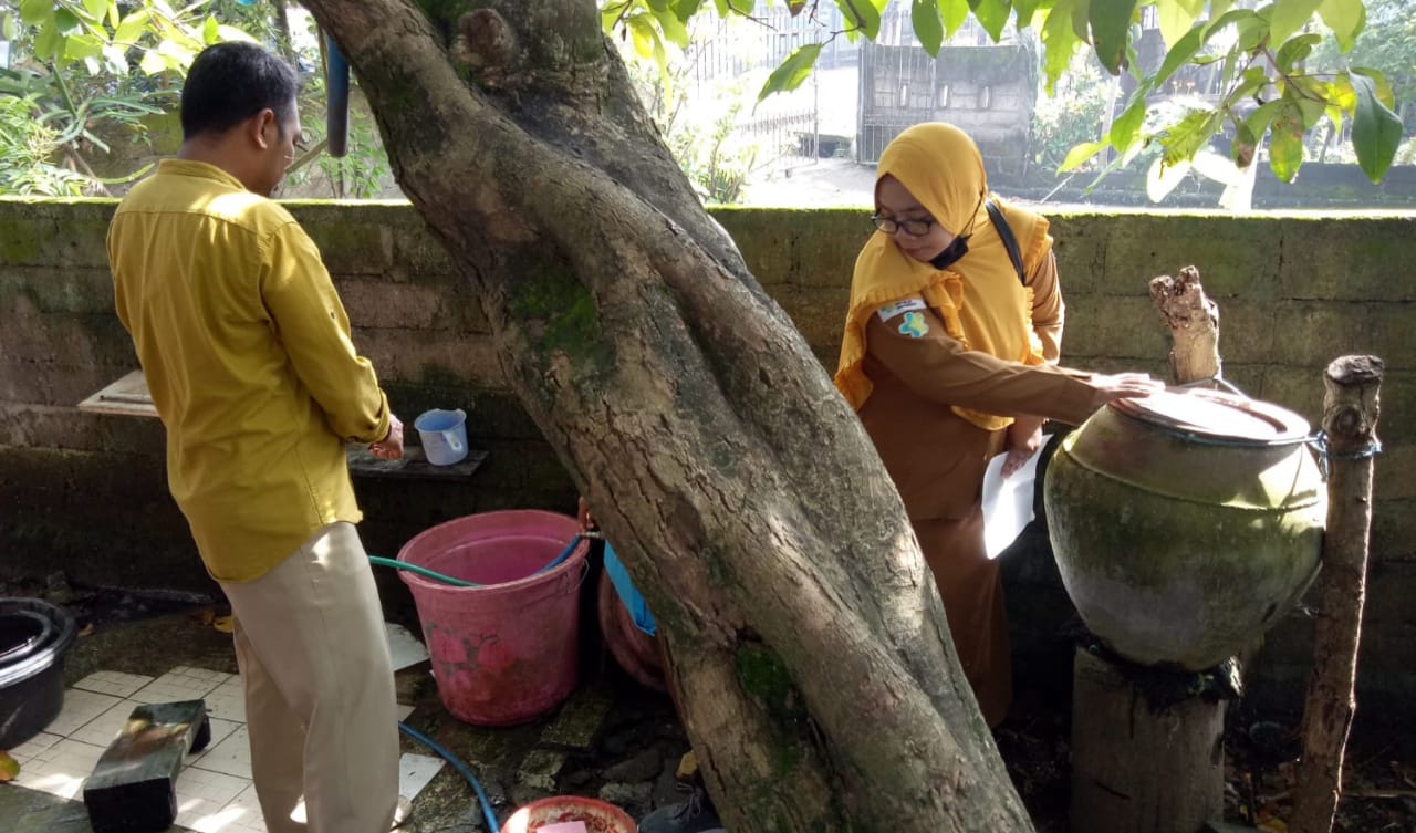 MENABUR BUBUK ABATE: Pegawai Dikes Loteng, saat menabur bubuk abate di salah satu rumah warga di Desa Marong, Praya Timur, Senin (20/12). (Dedi/Lombok Post)