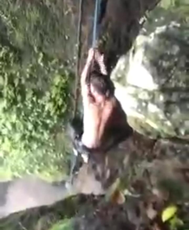 TERJEBAK: Seorang pemuda yang terjebak air bah di Sungai Oi Daru, Desa Sakuru, Kecamatan Monta, Kabupaten Bima, naik ke tebing menggunakan seutas tali, kemarin siang (9/1). (Repro Facebook Khairunisah Ahmad)