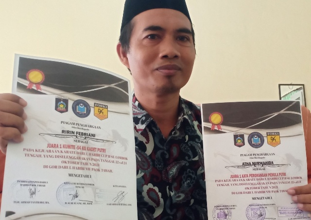 TUNJUKKAN: Kepala MTsN 4 Loteng Lalu Muhammad Khairi Asmuni saat menunjukkan piagam penghargaan juara satu lomba karate, Sabtu (22/1). (Dedi/Lombok Post)