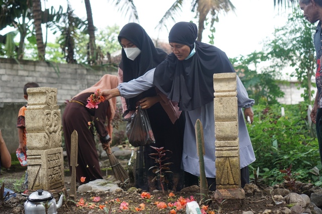 MENABUR BUNGA: Supriyani, warga Desa Dasan Borok, Kecamatan Suralaga menabur bunga di atas makam menantunya Julia Ningsih di TPU Dasan Borok, belum lama ini. Julia Ningsih merupakan salah satu pekerja migran dari Lombok Timur yang menjadi korban kapal ten