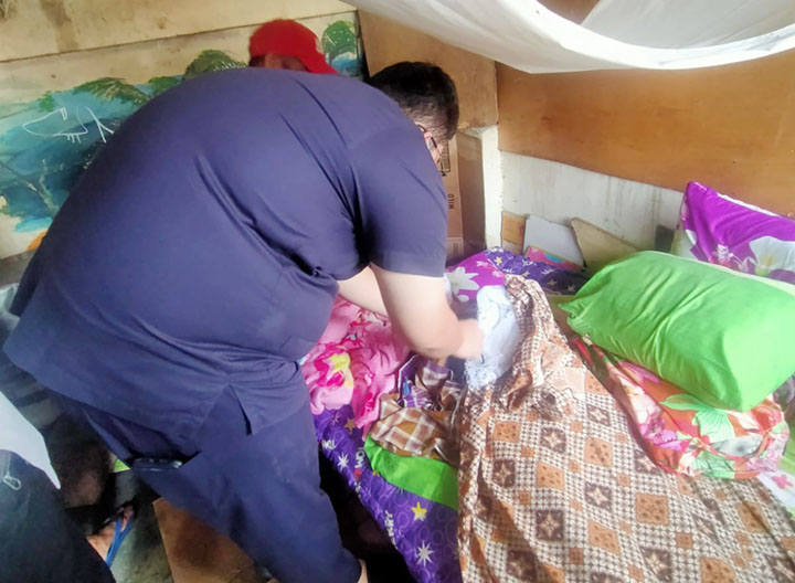 Petugas dari Polsek Sandubaya mengecek jenazah Sarifah di dalam kios di kawasan Terminal Mandalika, Senin (3/1). (Polsek Sandubaya for Lombok Post)