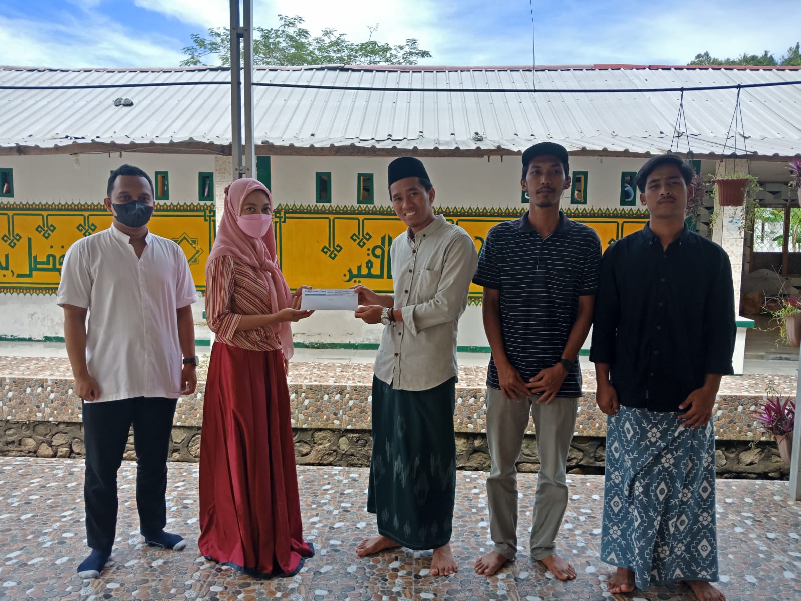 SEMOGA BERMANFAAT: Manager HRD Lombok Post Nancy Dwinana menyerahkan bantuan pembaca Harian Lombok Post ke mudabbir Yayasan Darul Anwar, Desa Kekait, Kecamatan Gunungsari Muhammad Azhani. (Farida/Lombok Post)