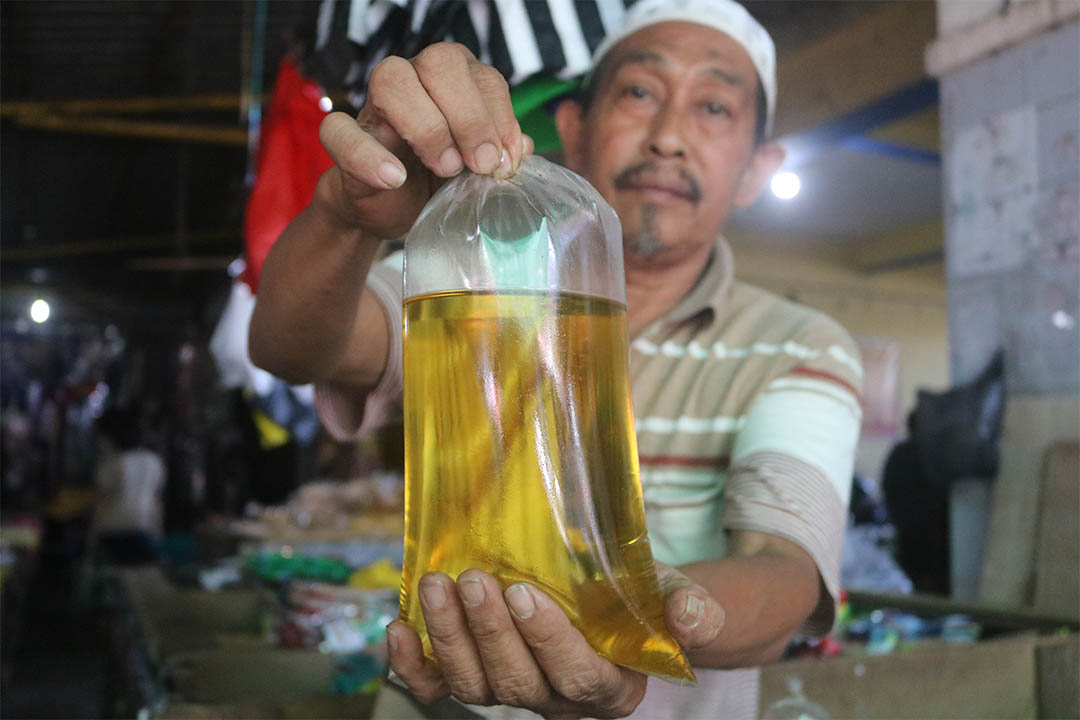 MASIH MAHAL: Seorang pedagang sembako di Pasar Kebon Roek memperlihatkan minyak goreng curah yang dijual di kiosnya, kemarin (6/2). (EKA/LOMBOK POST)