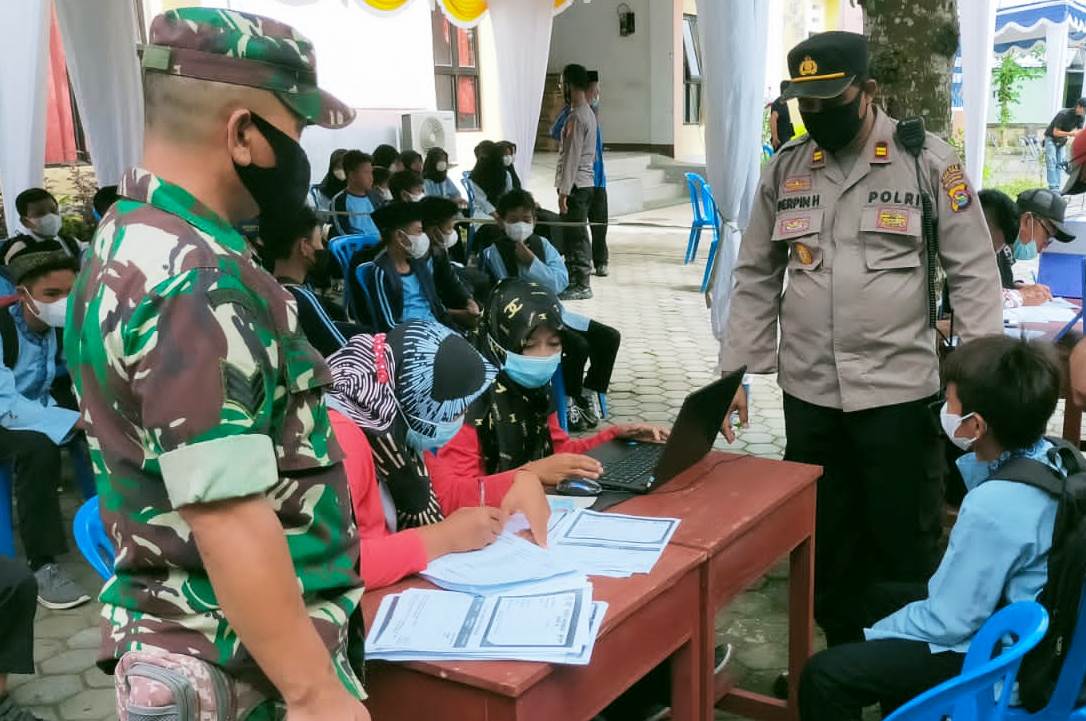 MENGECEK IDENTITAS: Para nakes saat mengecek identitas anak-anak sebelum disuntik vaksin di kantor camat Pujut, Loteng, Minggu (6/3). (Dedi/Lombok Post)