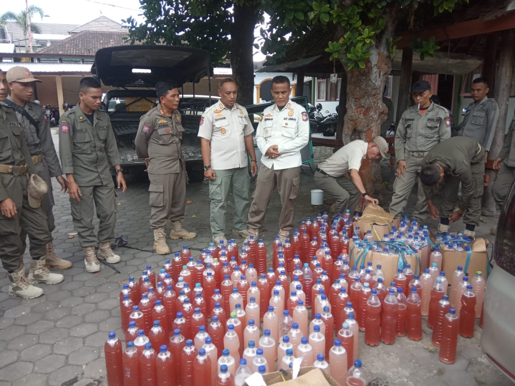 TUNJUKKAN: Kasatpol PP Lotim H Sudirman (lima dari kiri) menunjukkan barang bukti miras yang disita dalam operasi tangkap tangan, Rabu (23/3). (Fatih/Lombok Post)