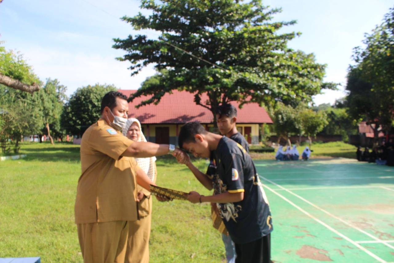BERIKAN REWARD: Kepala SMAN 1 Soromandi M Rifial Akbar memberikan reward kepada dua siswa peraih medali kejurnas pencak silat usai upacara, Senin (28/3). (SMAN 1 SOROMANDI FOR LOMBOK POST)
