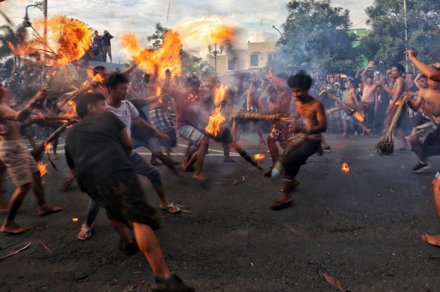 RITUAL TAHUNAN JELANG NYEPI: Dua warga Lingkungan Negarasakah Utara  dan Lingkunngan Sweta Cakranegara melakukan tradisi perang api di Bundaran Patung Tani Jalan Selaparang, Cakranegara, Kota Mataram, Rabu (2/3) lalu.( IVAN/LOMBOK POST)