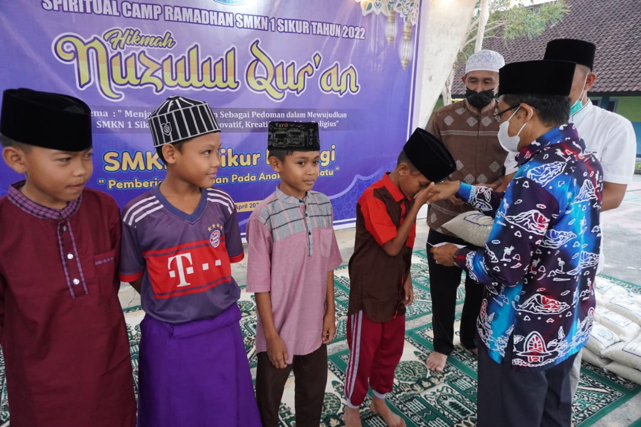 SANTUNI ANAK YATIM: Kepala Cabang Dikbud Lotim H Mashun menyerahkan santunan kepada anak yatim pada kegiatan Nuzulul Quran sekaligus buka bersama keluarga besar SMKN 1 Sikur di Kecamatan Sikur, Rabu (27/4) lalu. (Fatih/Lombok Post)