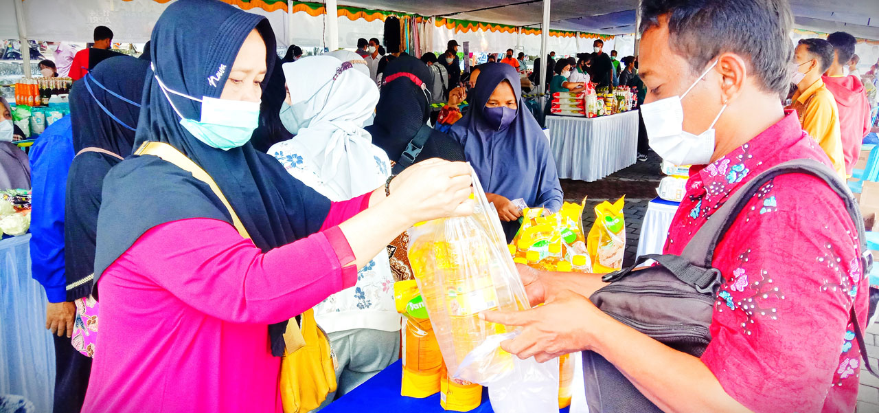 EKONOMI MEMBAIK: Seorang ibu-ibu terlihat membeli dua botol minyak goreng pada salah satu stand Pasar Rakyat Ramadan di Taman Sangkareang, Kota Mataram, Senin (11/4/2022). (Dewi/Lombok Post)