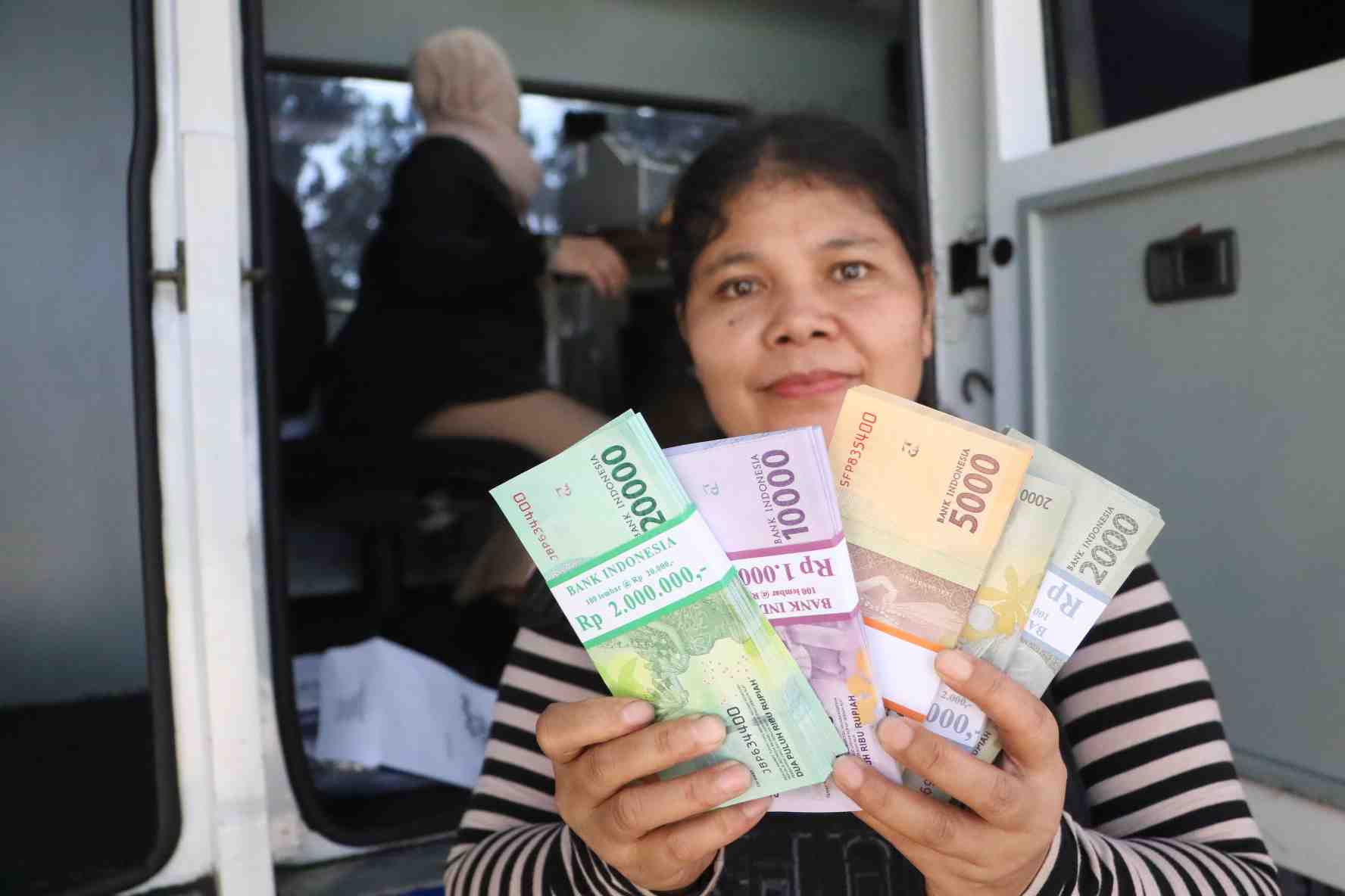 UNTUK KELUARGA: Seorang ibu menunjukkan sejumlah uang baru yang telah ditukar pada layanan keuangan keliling yang disediakan Bank Indonesia, di Kota Mataram, tahun lalu. Penukaran uang baru biasanya diperuntukkan untuk bagi-bagi THR kepada sanak saudara d