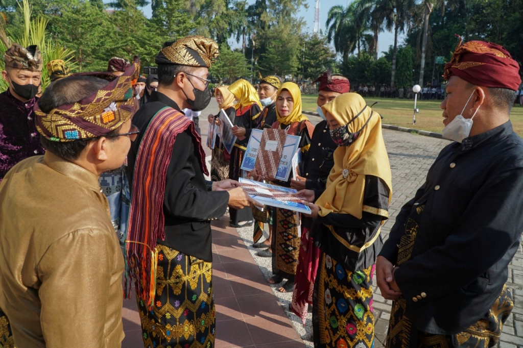PRESTASI: Sekda Lotim HM Juaini Taofik menyerahkan piagam penghargaan kepada guru berprestasi Lotim pada upacara peringatan Hardiknas di halaman kantor bupati Lotim, Jumat (13/5). (PKP Setda Lotim for Lombok Post)