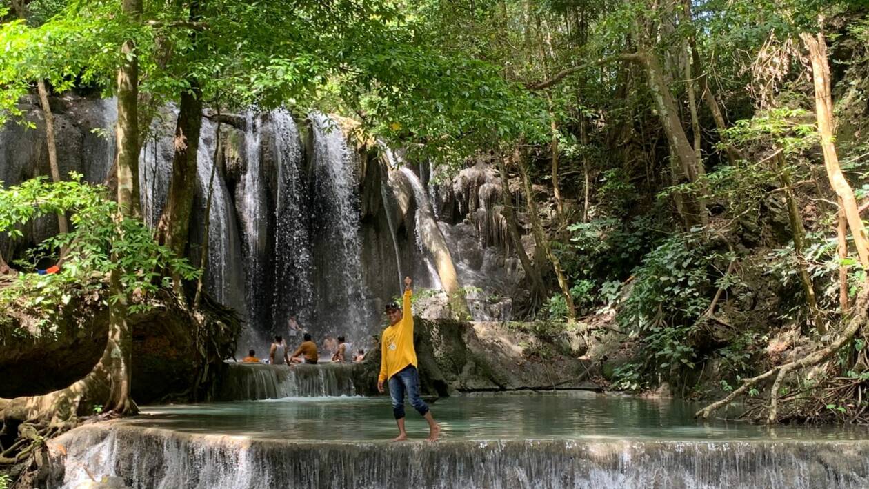 GALI POTENSI: Ketua ASTINDO NTB Sahlan M Saleh tengah berswafoto berlatar belakang Air Terjun Mata Jitu di Pulau Moyo, Sumbawa, Rabu (25/5). (Istimewa/Lombok Post)