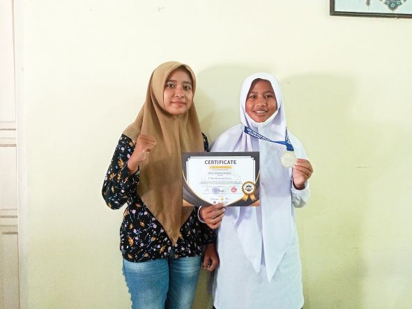 SANG JUARA: Baiq Yasmin Athirah, siswi MTsN 1 Mataram  yang meraih medali perak kejuaraan taekwondo piala rektor UNHI Denpasar foto bersama pelatih di madrasah setempat, Selasa (31/5) lalu.( ROJAI/LOMBOK POST)