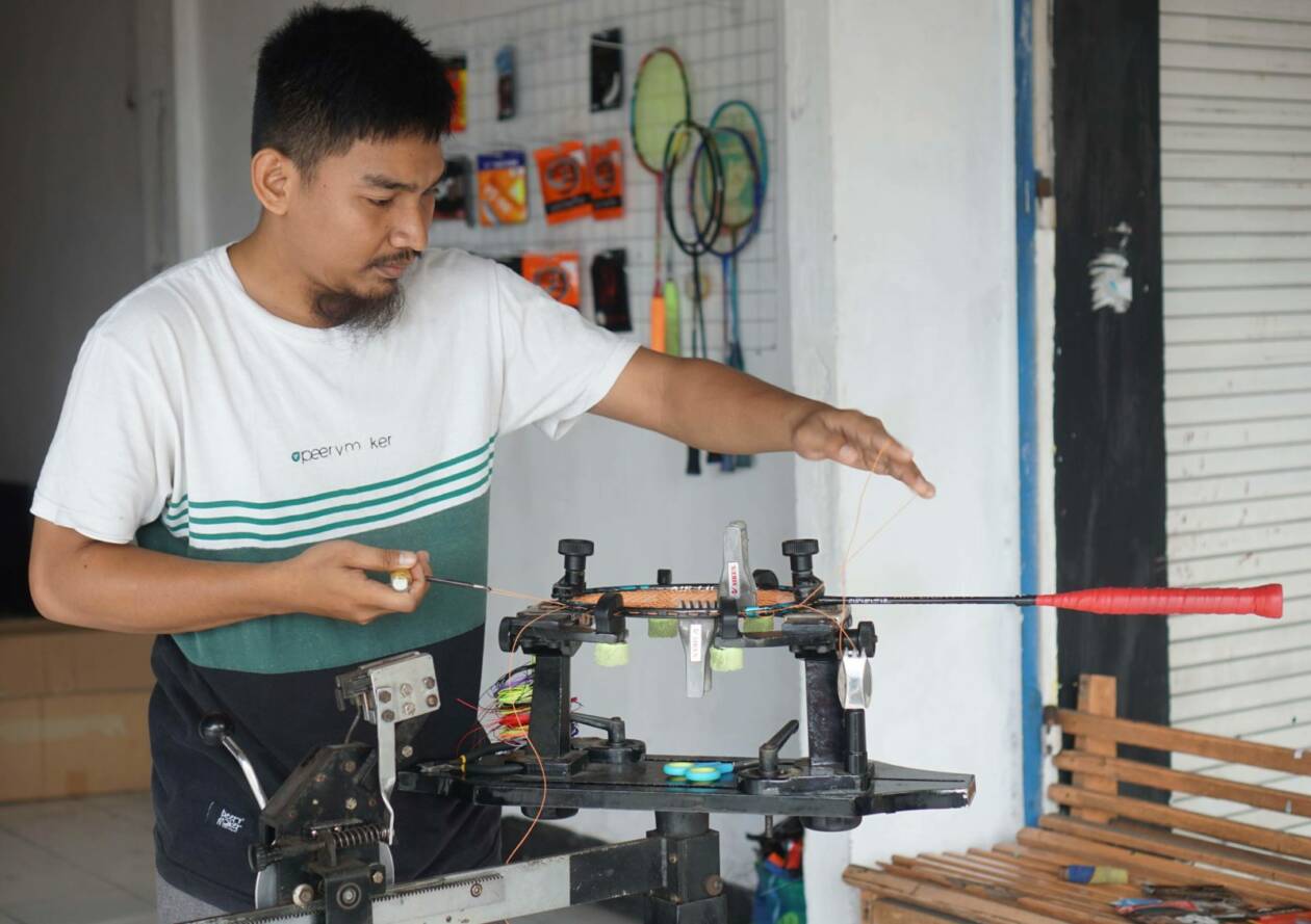 SENAR RAKET: Wardimansyah sedang memasang senar raket salah seorang pelangganannya di Dominate Badminton di Jalan Diponegoro, Kelurahan Majidi, Kecamatan Selong, beberapa waktu lalu. (Fatih/Lombok Post)