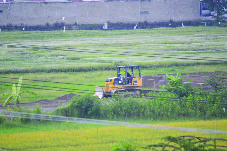 PERLU KOORDINASI: Sebuah alat berat dioperasikan di tengah-tengah areal pertanian. (Foto: Lombok Post)