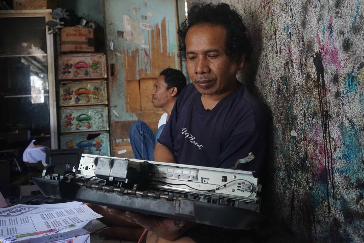 DOKTER PRINTER: Parhan Diari, tukang servis printer sedang membongkar salah satu printer milik pasiennya di Lingkungan Bermi, Kelurahan Pancor, Kecamatan Selong, Senin (18/7). (Fatih/Lombok Post)
