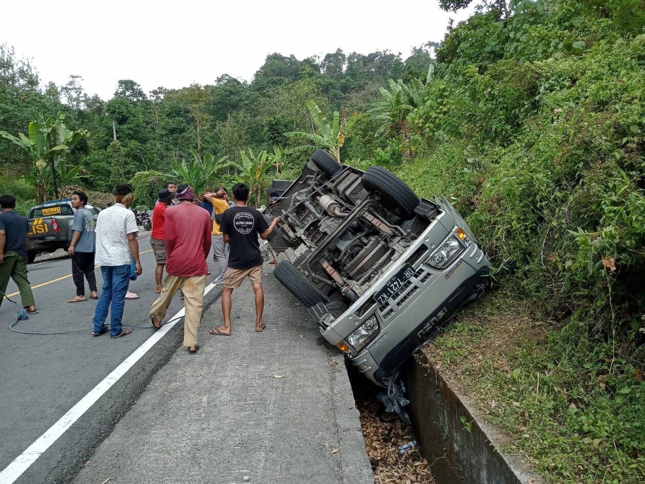 TERBALIK: Beberapa warga bersama anggota Polsek Sembalun sedang menarik sebuah minibus yang terbalik di jalan raya Pusuk Desa Sajang, Kecamatan Sembalun, Minggu (7/8).  (Polsek Sembalun for Lombok Post)