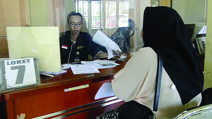 BELUM BERLAKU: Seorang warga mengurus administrasi kependudukan di kantor Dinas Dukcapil Kota Mataram, belum lama ini. Saat ini Dinas Dukcapil masih menunggu regulasi untuk penggunaan NIK sebagai NPWP. (Foto: Rojai/Lombok Post)